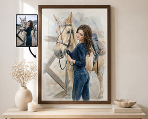 A framed watercolor portrait print of a woman in blue jeans standing beside a light-colored horse, displayed on a light wood console table in a styled interior. A small inset photo in the upper left shows the source reference image that appears to be transformed into the artwork.