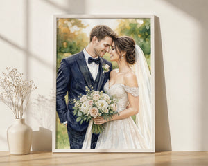 A framed custom wedding portrait print leaning against a wall on a wooden surface, next to a small vase with dried stems. The artwork shows a bride in a white gown holding a bouquet and a groom in a navy suit.
