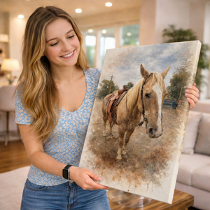 A smiling woman holds up a large canvas print featuring a painted horse in a rustic outdoor scene, set in a bright, modern living room.