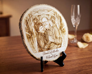 A personalized wooden slice plaque on a black stand, featuring a laser-engraved portrait of a couple and the text 'Edward & Martha 30 Years of Love', displayed on a wooden table with a wine glass in the background.