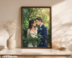 A framed custom wedding portrait print displayed on a light wood console table. The print features an illustration of a bride in a white dress and a groom in a navy blue suit holding a bouquet of white flowers, set against a lush green background.