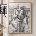 A framed black and white custom pencil sketch portrait of a woman and a horse, shown hanging on a beige wall next to a small inset photo of the reference image. The product is the framed art print itself.