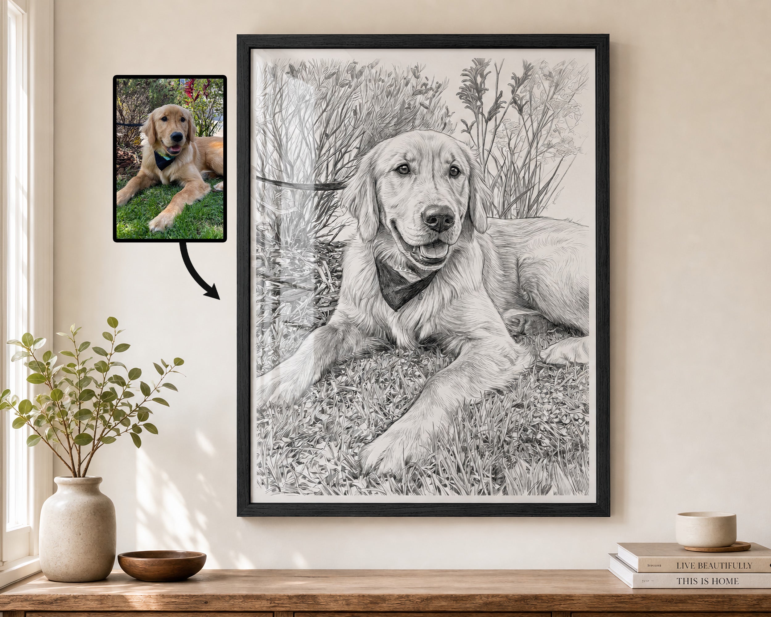 A framed black-and-white portrait drawing of a golden retriever dog hanging on a beige wall above a wooden shelf with a vase and books. To the left, a smaller inset photo of the dog appears with an arrow pointing toward the artwork, suggesting a custom pet portrait service.