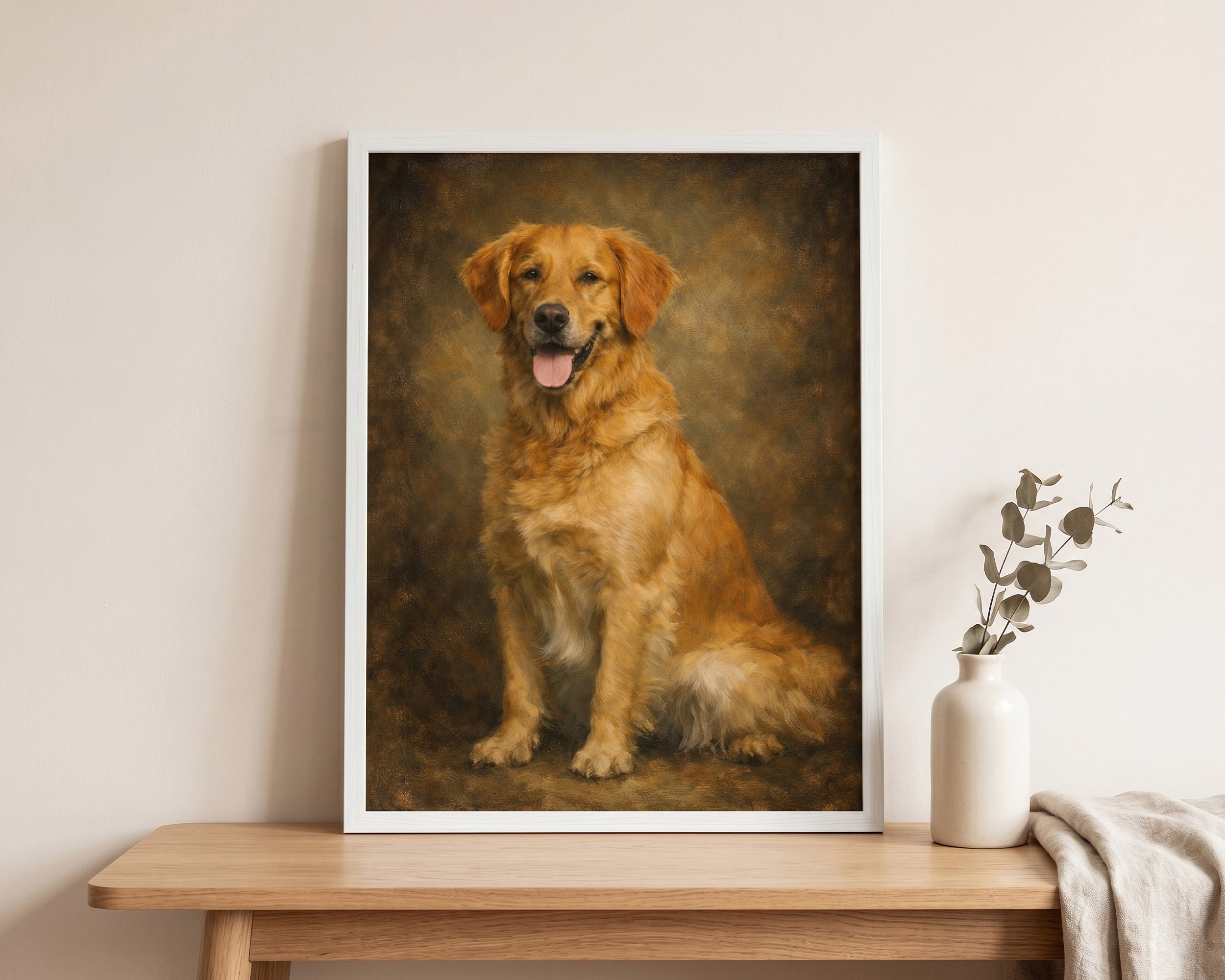 A framed custom pet portrait of a golden retriever dog, displayed on a light wood table next to a white ceramic vase with dried leaves.