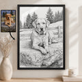 A framed black-and-white custom dog portrait of a Labrador Retriever is displayed on a wall in a styled room setting next to a vase with dried stems and a candle. A small inset photo of the reference dog lies to the left with an arrow pointing to the portrait.