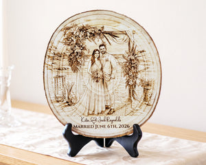 A round wooden wedding plaque with engraved couple portraits and the text 'Kate & Jack Reynolds MARRIED JUNE 6TH, 2026', displayed on a black stand on a light table runner.